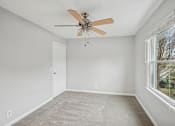 Thumbnail 7 of 11 - A room with a ceiling fan and a window.