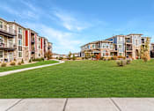 Thumbnail 18 of 32 - A row of apartment buildings with a green lawn in front.