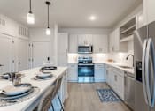 Thumbnail 24 of 29 - A modern kitchen with a dining table set for two.