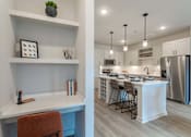 Thumbnail 11 of 29 - A modern kitchen with a white desk and orange chair.