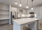 Thumbnail 25 of 29 - A modern kitchen with a white island and stainless steel appliances.