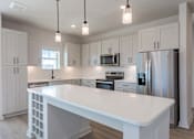 Thumbnail 29 of 29 - A modern kitchen with a white island and stainless steel appliances.