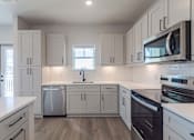 Thumbnail 26 of 29 - A kitchen with white cabinets and appliances.