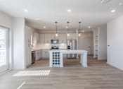 Thumbnail 20 of 29 - A modern kitchen with a white island and pendant lights.
