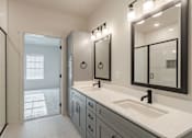 Thumbnail 17 of 29 - A bathroom with a sink, mirror, and a shower.