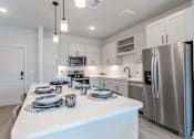 Thumbnail 19 of 29 - A modern kitchen with a white island and stainless steel appliances.