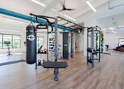 Thumbnail 2 of 35 - A gym with a punching bag and weightlifting equipment.