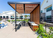 Thumbnail 24 of 35 - A patio with a table and chairs under a wooden roof.