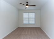 Thumbnail 22 of 36 - A room with a ceiling fan and carpeted floor.