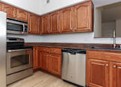 Thumbnail 12 of 36 - A kitchen with wooden cabinets and a black dishwasher.