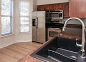 Thumbnail 11 of 36 - A kitchen with a black sink and stainless steel appliances.
