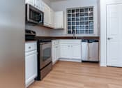 Thumbnail 19 of 36 - A kitchen with white cabinets and a black oven.