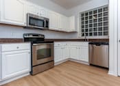 Thumbnail 18 of 36 - A kitchen with white cabinets and stainless steel appliances.