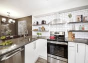 Thumbnail 3 of 34 - Luxury Apartments for Rent in Seattle- Union Bay- Kitchen with Tile Backsplash with Stainless-Steel Appliances and Quartz Countertops