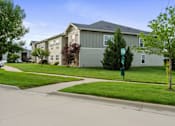 Thumbnail 10 of 28 - Apartment complex with a green lawn in front.