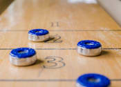 Thumbnail 65 of 65 - A shuffleboard table with blue and white pucks.