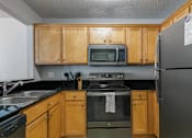 Thumbnail 26 of 41 - A kitchen with wooden cabinets and a black refrigerator.