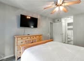 Thumbnail 37 of 41 - A bedroom with a bed, dresser, and a flat screen TV mounted on the wall.