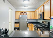 Thumbnail 28 of 41 - A kitchen with wooden cabinets and a black countertop.