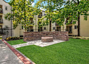 Thumbnail 4 of 41 - A small garden with a stone wall and a bench in front of apartment buildings.