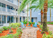 Thumbnail 22 of 24 - a courtyard with palm trees and chairs in front of a building