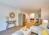 Thumbnail 4 of 24 - a living room with a white couch and a stainless steel refrigerator