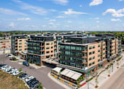 Thumbnail 1 of 53 - A modern building complex with a parking lot in front.