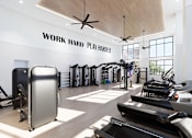Thumbnail 7 of 21 - A gym with a variety of equipment and a sign that says "Work Hard Play Harder".