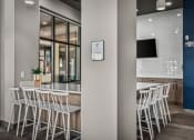 Thumbnail 7 of 61 - a communal area with white chairs in front of a bar and a television