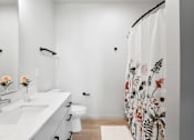 Thumbnail 40 of 53 - A white bathroom with a floral shower curtain.