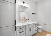 Thumbnail 47 of 53 - A white bathroom with a toilet, sink, and mirror.