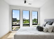 Thumbnail 32 of 53 - A bedroom with a large bed and a view of the outside through the windows.