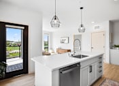 Thumbnail 38 of 53 - A modern kitchen with a large island and pendant lights.
