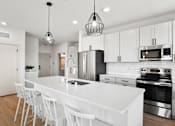 Thumbnail 31 of 53 - A modern kitchen with white cabinets and a white island.