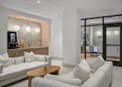 Thumbnail 15 of 26 - A white couch with a wooden table in front of a wall with a patterned wallpaper.