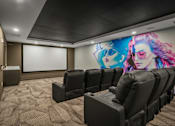 Thumbnail 22 of 26 - A movie theater with black chairs and a large screen.