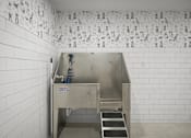 Thumbnail 23 of 26 - A stainless steel sink in a white tiled bathroom.