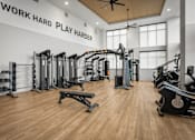 Thumbnail 14 of 26 - A gym with a variety of equipment and a ceiling fan.