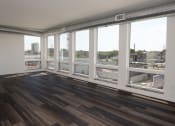Thumbnail 35 of 84 - A living room with hardwood floors and a large window with a view of a city at The Landing at 1001 NP, Fargo, ND, 58102