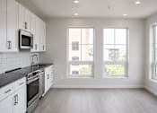 Thumbnail 3 of 17 - Modern kitchen with large windows and light flooring at The Avery - Residential Apartments, Fargo