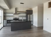 Thumbnail 20 of 27 - a kitchen with a black island and stainless steel appliances at Riverhouse Apartments, Fargo