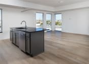 Thumbnail 19 of 27 - an open kitchen and living room with a large window and a black counter top at Riverhouse Apartments, Fargo, North Dakota