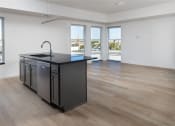 Thumbnail 6 of 27 - an open kitchen and living room with a large window and a black counter top at Riverhouse Apartments, Fargo, ND 58102