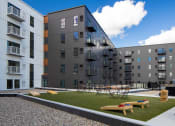 Thumbnail 10 of 27 - an exterior view of an apartment complex with tables and grass at Riverhouse Apartments, Fargo, ND