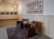 Thumbnail 2 of 27 - two leather chairs in a room with pictures on the wall at Riverhouse Apartments, Fargo, North Dakota