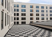 Thumbnail 7 of 17 - Courtyard with checkered tile flooring and building facade at The Avery - Residential Apartments, Fargo, North Dakota