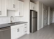 Thumbnail 2 of 17 - Contemporary kitchen with gray countertops and white backsplash at The Avery - Residential Apartments, Fargo