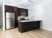 Thumbnail 34 of 37 - a kitchen with dark wood cabinets and stainless steel appliances  at RoCo Apartments, Fargo, ND, 58102