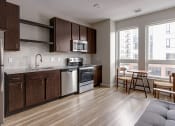 Thumbnail 24 of 37 - a kitchen with dark wood cabinets and stainless steel appliances  at RoCo Apartments, Fargo, North Dakota 58102