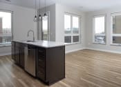 Thumbnail 30 of 37 - an open kitchen with a large island with a sink and a dishwasher  at RoCo Apartments, Fargo, North Dakota 58102